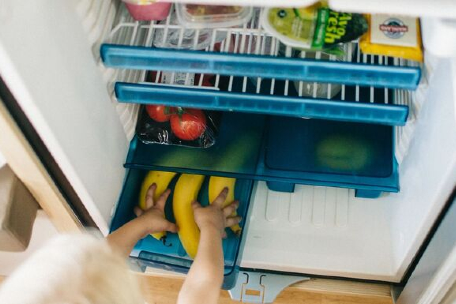reaching in motorhome fridge for food in the bottom drawer