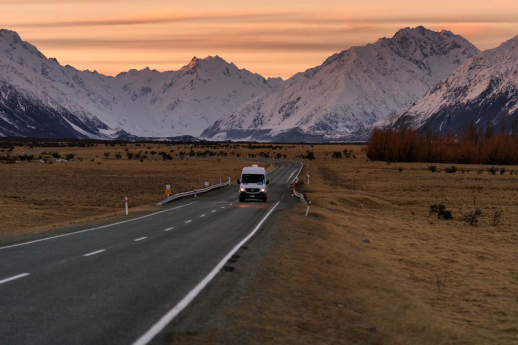 Motorhome driving down New Zealand road with wintery snow mountains in the background