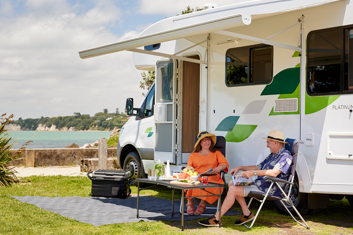 Couple outside KEA motorhome enjoying the sun under the awning of motorhome 