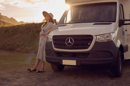 lady leaining on motorhome while sun is setting