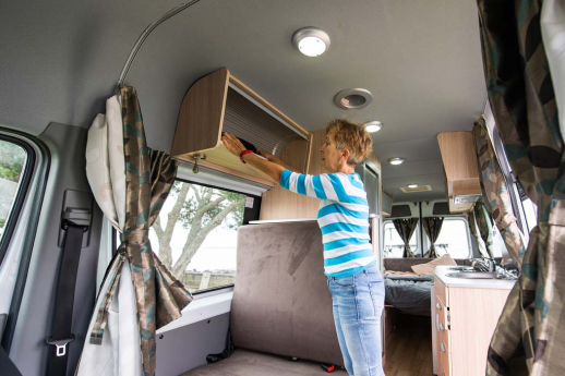 Lady reaching in storage compartment in spacious motorhome